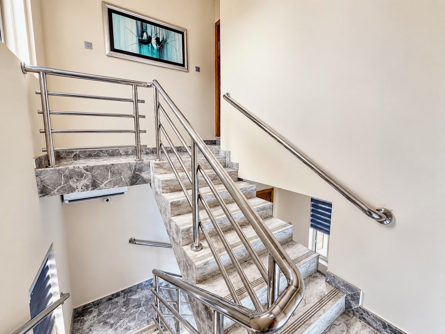 A staircase with marble steps and metal handrails, leading to an upper floor.