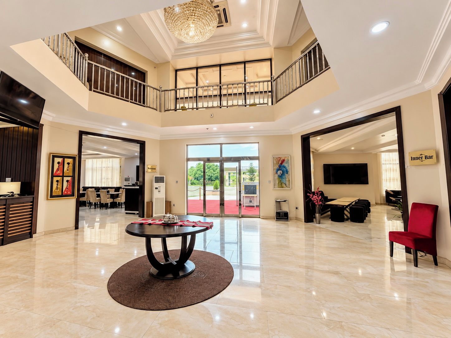 A spacious lobby with a central round table, a staircase, and a view of the outdoors.