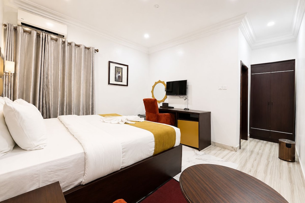 Een hotelkamer met een bed, een bureau, een televisie, een kledingkast en een badkamer.