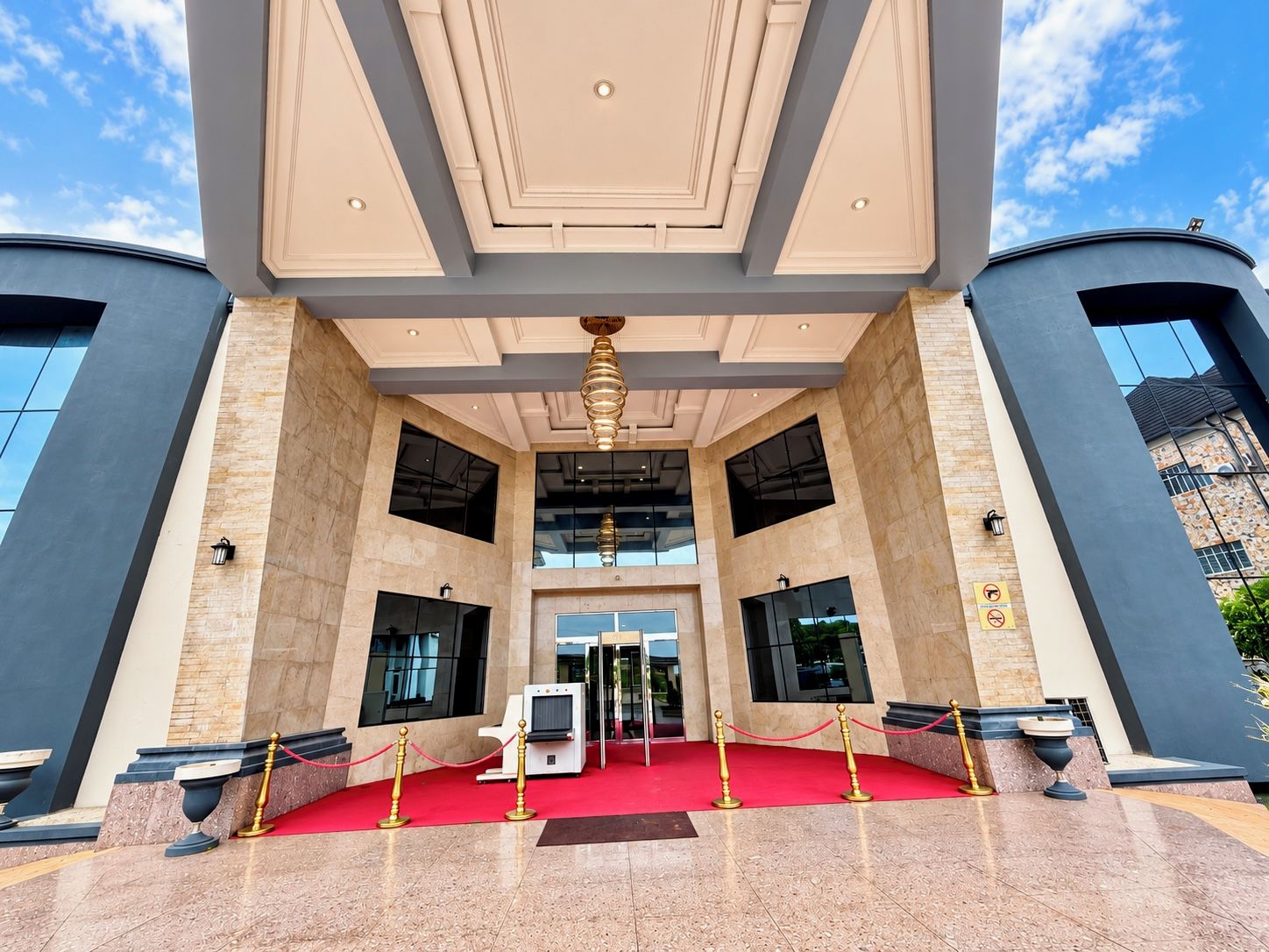 L’entrée d’un hôtel, avec un tapis rouge, des portes à double battant et un design moderne.