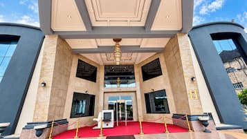 L’entrée d’un hôtel, avec un tapis rouge, des portes à double battant et un design moderne.