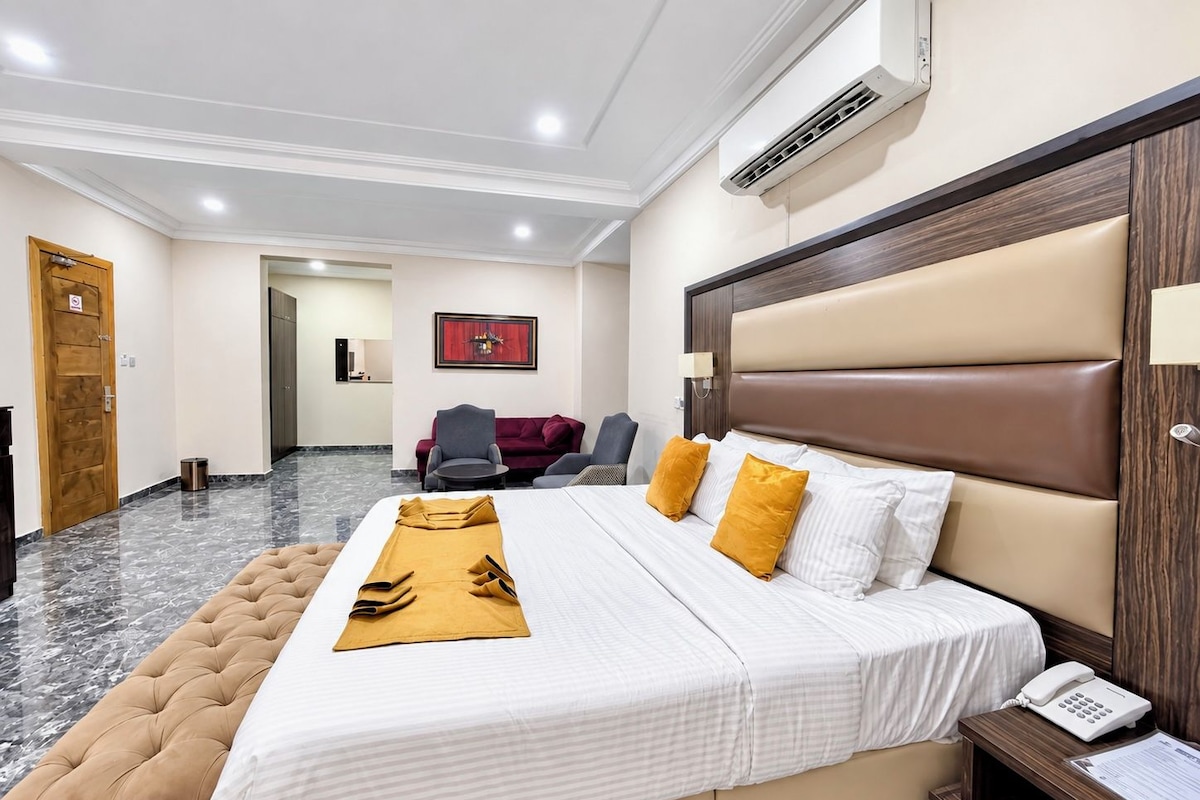 Een hotelkamer met een groot bed, een bedtafeltelefoon, een houten hoofdeinde en een marmeren vloer.