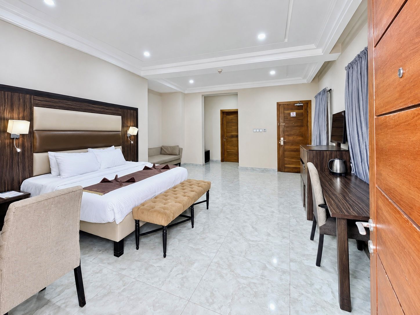 Una habitación de hotel con una cama grande, un escritorio, una silla, un sofá y una mesa de comedor.