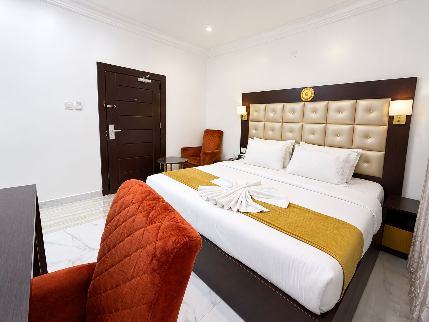 Een hotelkamer met een bed, een stoel, een bureau en een deur.
