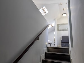 A staircase with a wooden handrail leading to a landing with a bench and a mirror. - Cozy Accommodation, Central Madrid (Madrid)