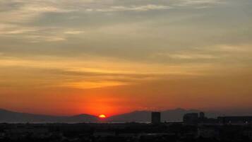 A sunset over a cityscape with buildings and a mountain in the background.