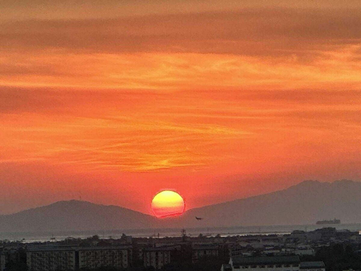 Un atardecer sobre un paisaje costero con una montaña al fondo.