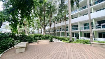 Un hotel de varios pisos con una terraza de madera, palmeras y fachada blanca.