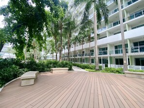 A multi-story hotel with a wooden deck, palm trees, and a white building facade. - Citispace Suites Azure Urban Resort  (Parañaque)