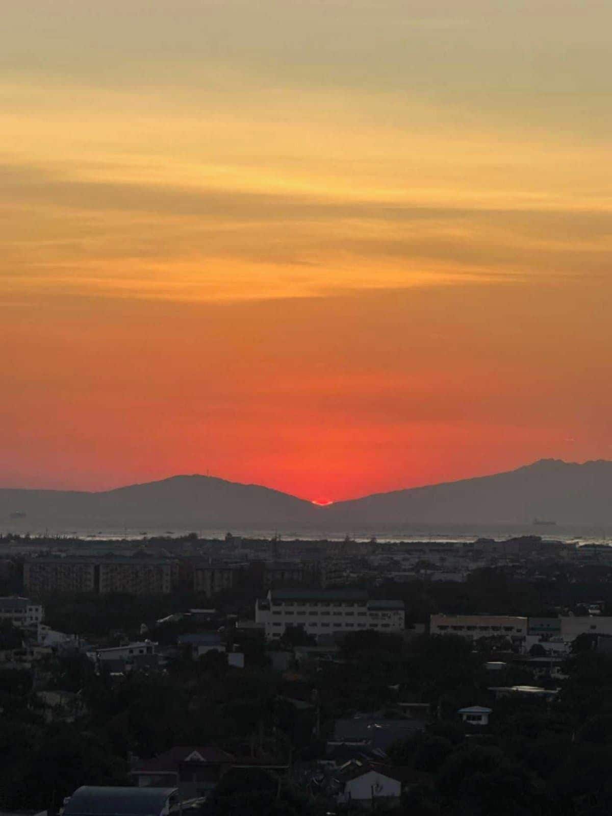 Un paisaje urbano al atardecer con montañas en el fondo.