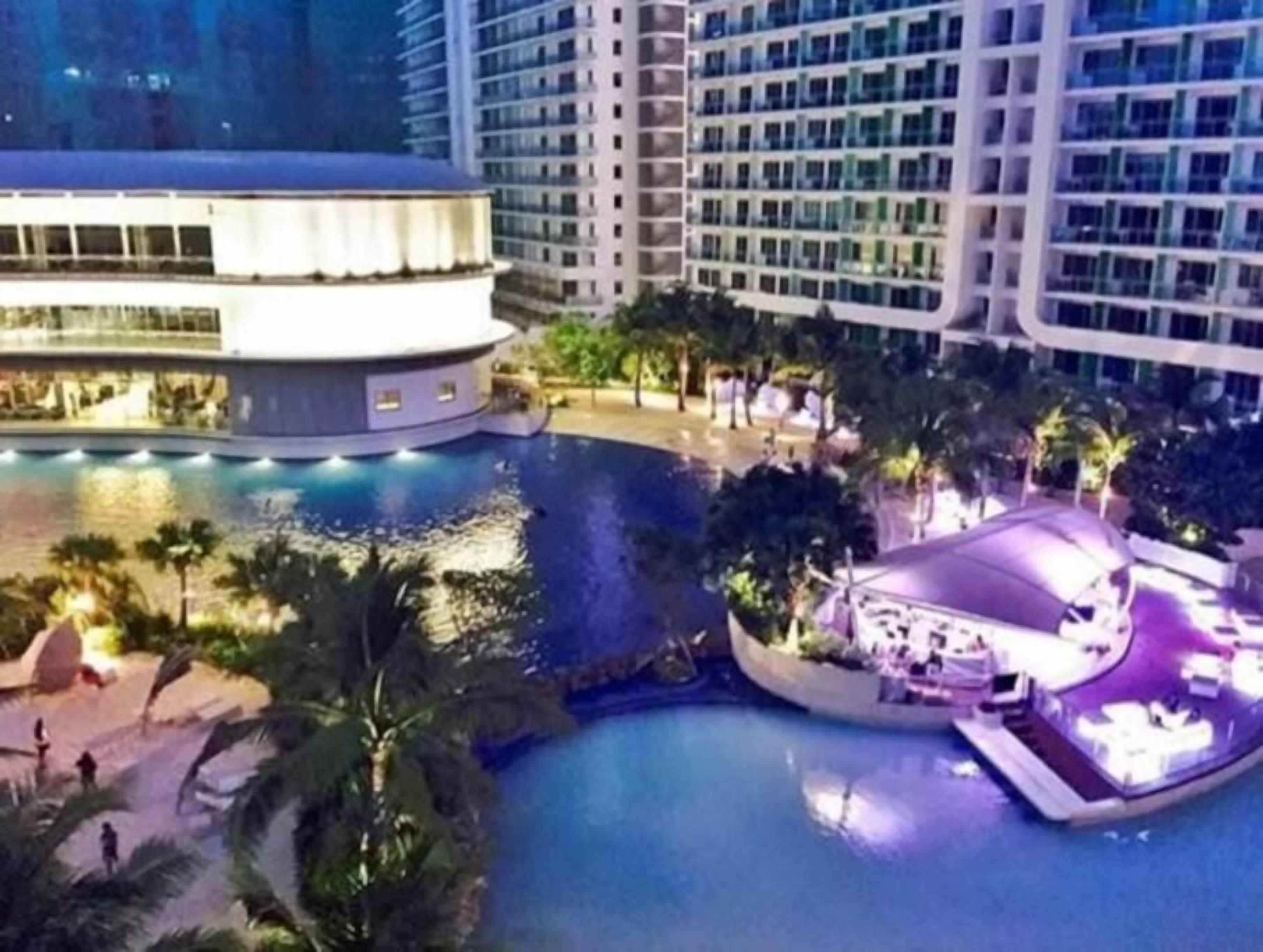 Un hotel con piscina, edificio circular y zona ajardinada con palmeras.