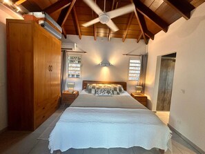 Ein Schlafzimmer mit einem großen Bett, einem Holzschrank, einem Deckenventilator und zwei Nachttischen mit Lampen.