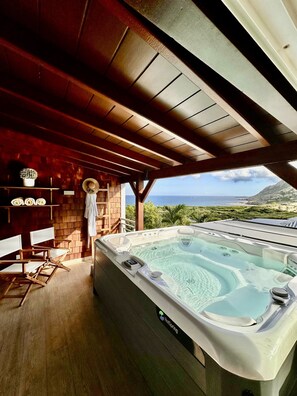 A hot tub with a view of the ocean, wooden flooring, and a rustic interior. - Villa des Rocher – Private Jacuzzi, Ocean View, and Serenity in Saint Barth (Grand Fond)