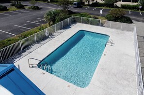 A rectangular pool with a metal ladder and a no diving sign, surrounded by a white fence and a parking lot in the background. - Cozy 1 BR in Sea Mist! (Carolina Beach)