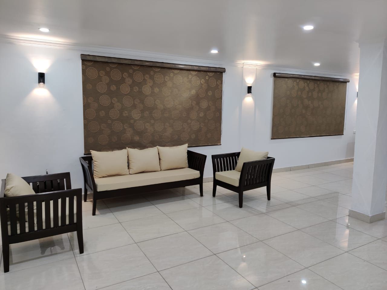 A modern interior with a sofa, two armchairs, and a patterned wall.