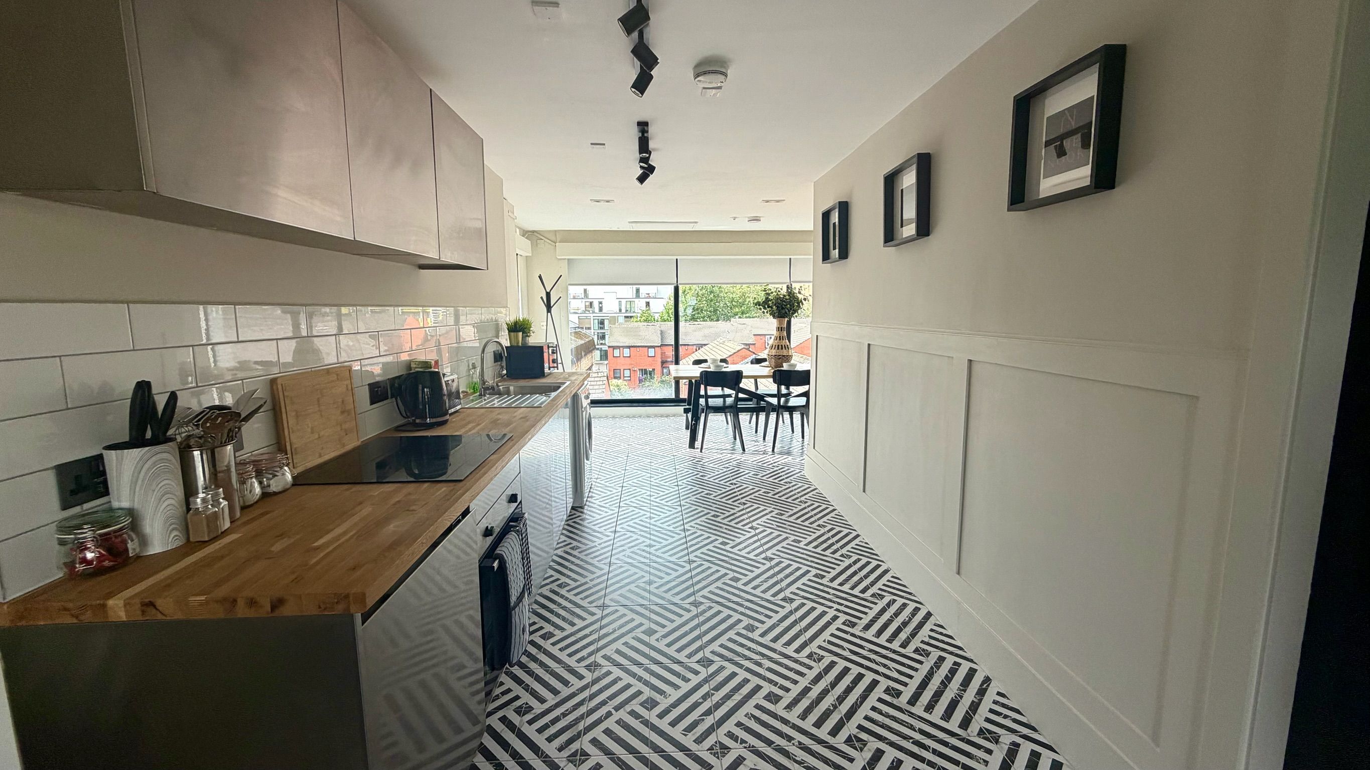 A modern kitchen with a wooden countertop, stainless steel appliances, and a patterned floor.