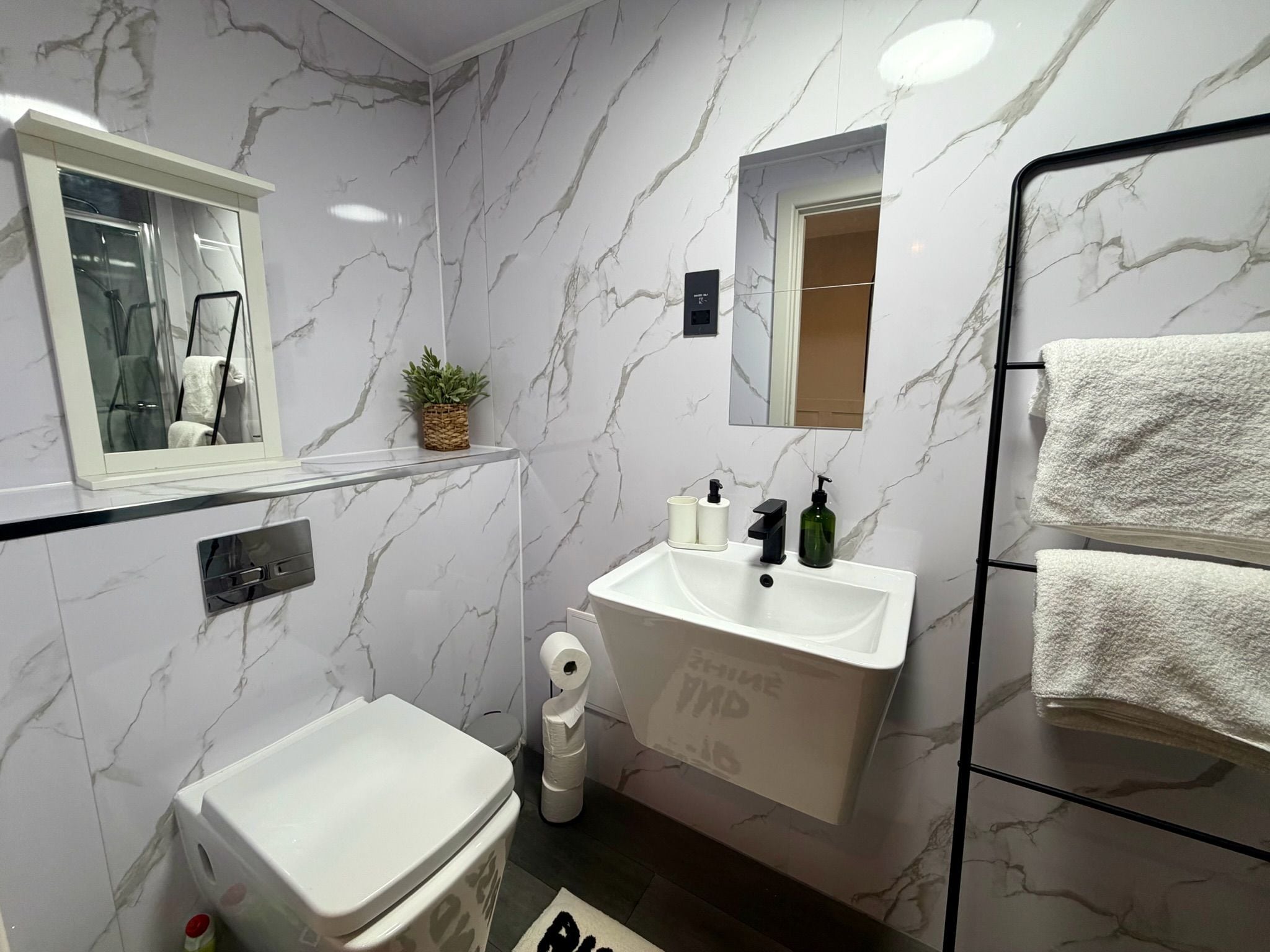A bathroom with a white sink, mirror, and towel rack.