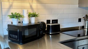 A kitchen with a microwave, toaster, and a stainless steel sink. - Celestial Apartments (Manchester)