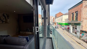 A balcony with a view of a street, a sofa, and a television.