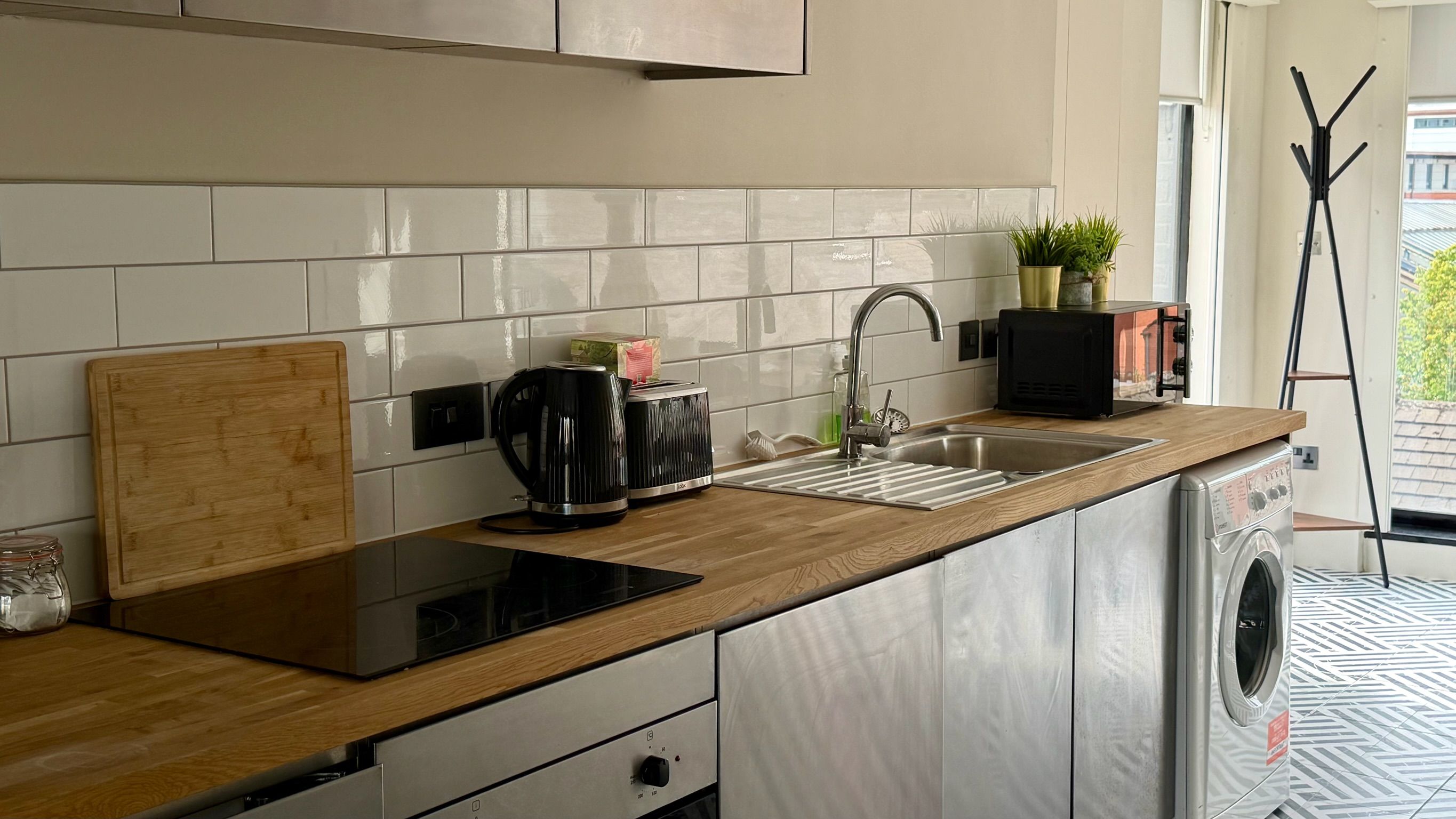 Una cocina moderna con encimera de madera, cafetera, tostadora, lavabo y lavadora.