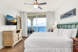 Ett hotellrum med en stor säng, en byrå i trä, en tv och en balkong med utsikt över havet.