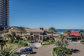 Ein Hotel mit einem zentralen Eingang, Palmen und Blick aufs Meer.