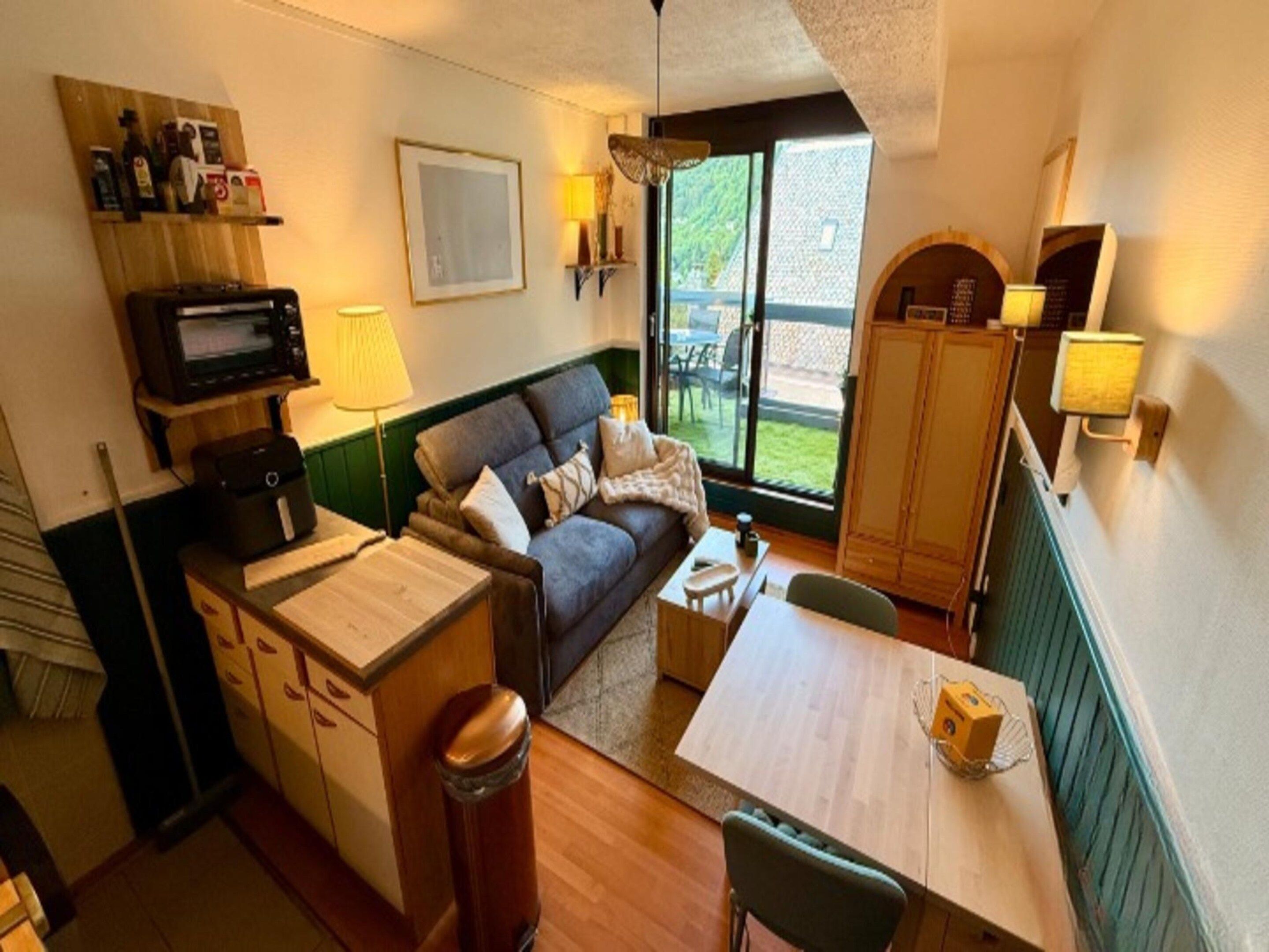 A compact living space with a sofa, a small table, a cabinet, and a microwave.