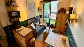 A compact living space with a sofa, a small table, a cabinet, and a microwave.