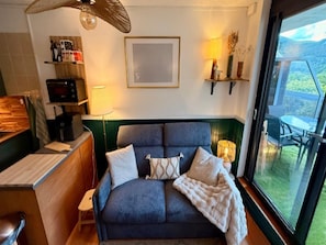 Quarto com cama, escrivaninha, cadeira, luminária e vista para o exterior.
