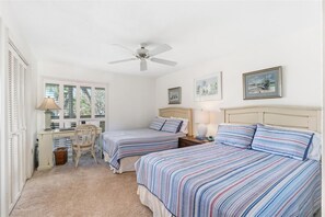 A bedroom with two beds, a desk, a chair, a ceiling fan, and artwork on the walls. - Whitney Hideaway 151 (Longboat Key)