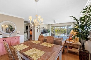 A spacious living room with a large dining table, a ceiling fan, and a view of the outdoors. - Whitney Hideaway 151 (Longboat Key)