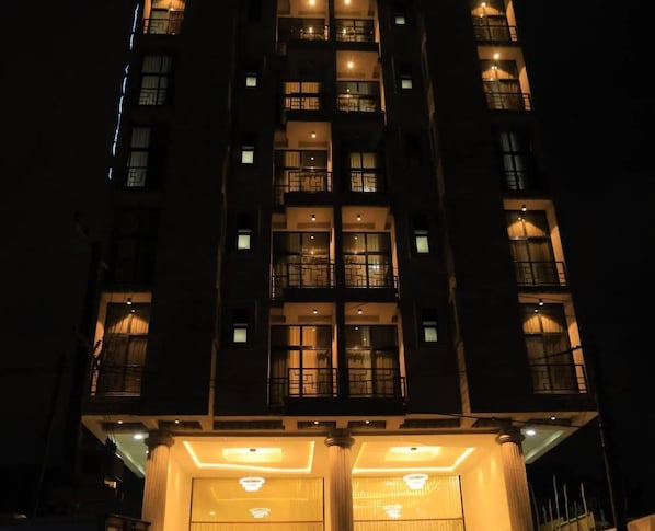 Un edificio de varios pisos con ventanas e balcones iluminados durante la noche.
