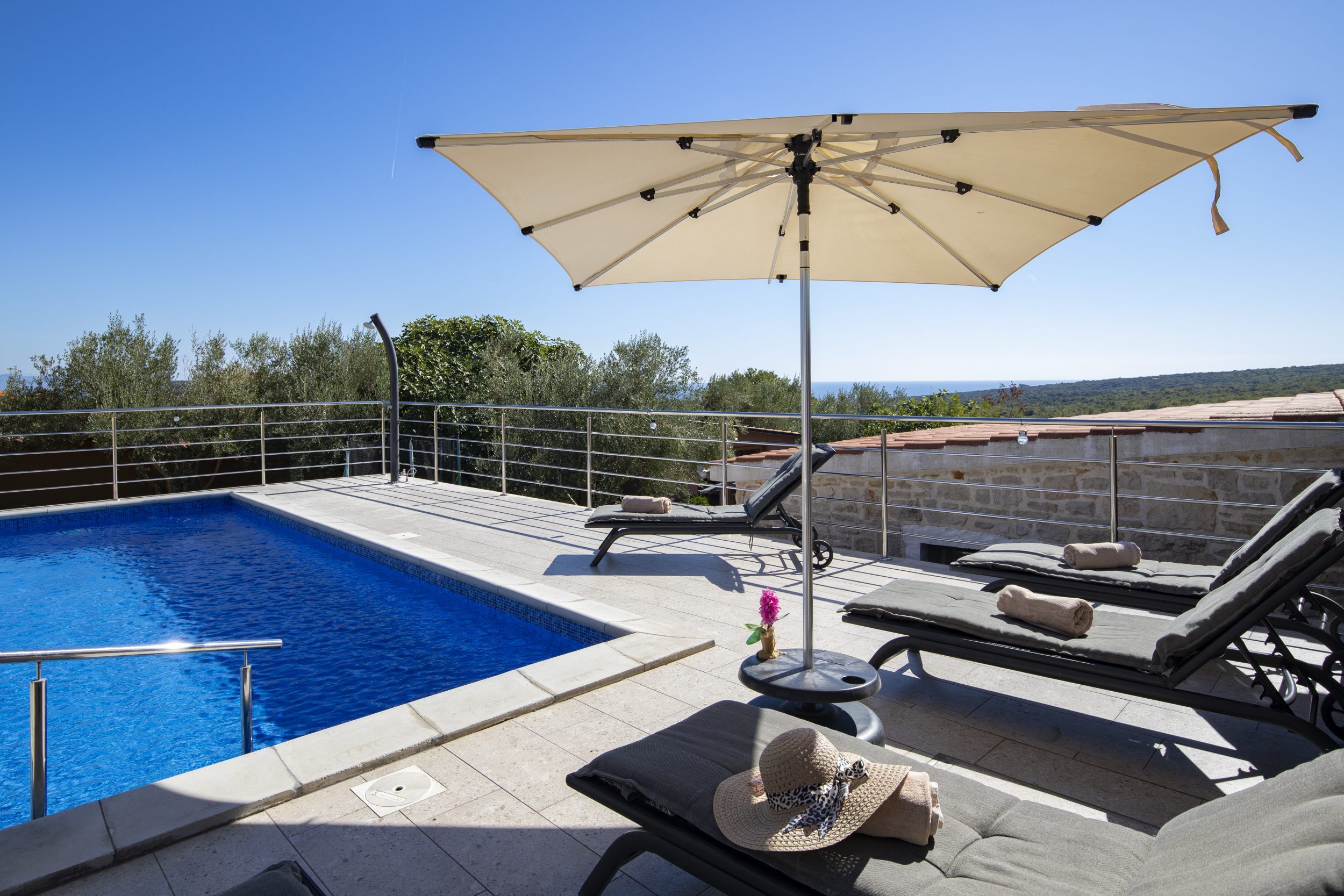 A rooftop pool area with lounge chairs and an umbrella.