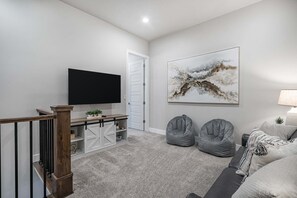 Ein modernes Wohnzimmer mit Fernseher, einem großen abstrakten Gemälde und zwei Sitzsäcken.
