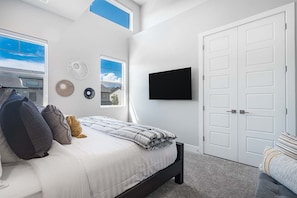 A bedroom with a bed, a TV, a door, and a window. - Snow Canyon Oasis #66 3 Bedroom Townhouse (Santa Clara)