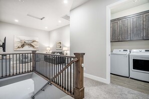 Ein modernes Interieur mit Treppe, einem Wohnbereich mit Sofa und Lampen sowie einem Hauswirtschaftsraum mit Geräten.