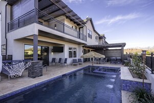 Uma casa de dois andares com piscina, área de estar externa e pérgola.