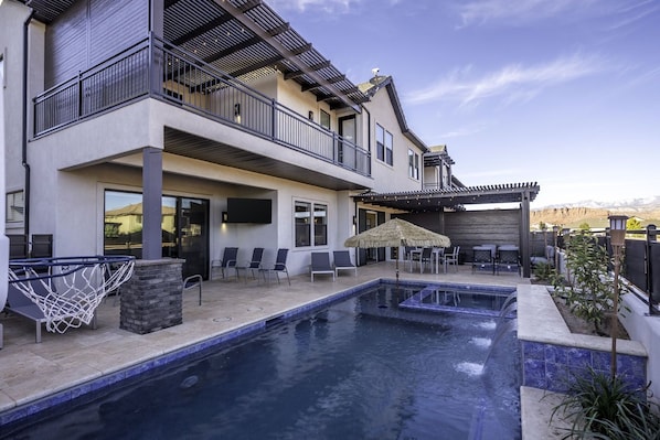 Uma casa de dois andares com piscina, área de estar externa e pérgola.