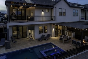 A two-story house with a balcony, a swimming pool, and outdoor seating. - Snow Canyon Poolhouse 8 Bedroom Home (Santa Clara)