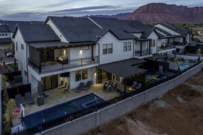 Une maison moderne à deux étages dotée d’un grand jardin, comprenant une piscine et des espaces de détente en plein air.