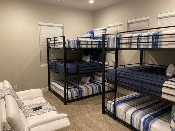 Une chambre avec des lits superposés, un canapé blanc et un plaid à motifs.