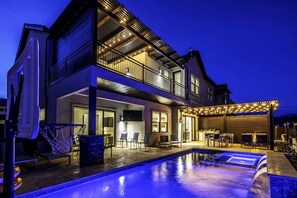 Uma casa de dois andares com piscina, área de estar externa e varanda coberta.
