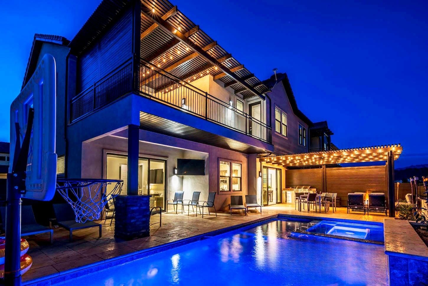 A two-story house with a swimming pool, outdoor seating, and a covered patio area.