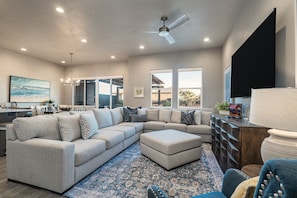 A modern living room with a sectional sofa, ottoman, and a ceiling fan. - Snow Canyon Escape Private Pool #65 5 Bedroom Townhouse (Santa Clara)