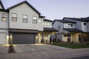 A residential building with a garage, a covered patio, and a well-maintained lawn. - Snow Canyon Escape Private Pool #65 5 Bedroom Townhouse (Santa Clara)