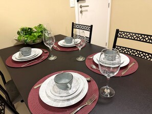 A dining table set with plates, glasses, and cutlery. - Furnished 2-bedroom apartment in Ponta Negra, condominium with pool, close to the beach. (Natal)