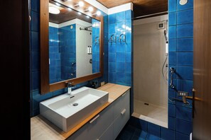 A bathroom with a white sink, a mirror, and blue-tiled walls. - Residenza Adua - 100mt dall'Arena  (Verona)