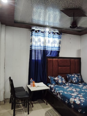 Een kamer met een bed, een tafel, een stoel en een raam met gordijnen.