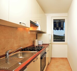 A compact kitchen with a gas stove, a sink, and a window overlooking a scenic landscape. - Adorable 1-bedroom apartment with AC, beautiful sea view in charming Dubrovnik (Dubrovnik)