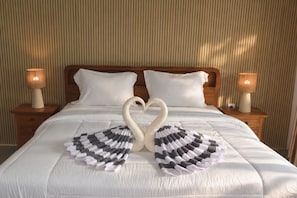 Una cama con disposición de almohadas en forma de corazón y una almohada decorativa en la cabecera.